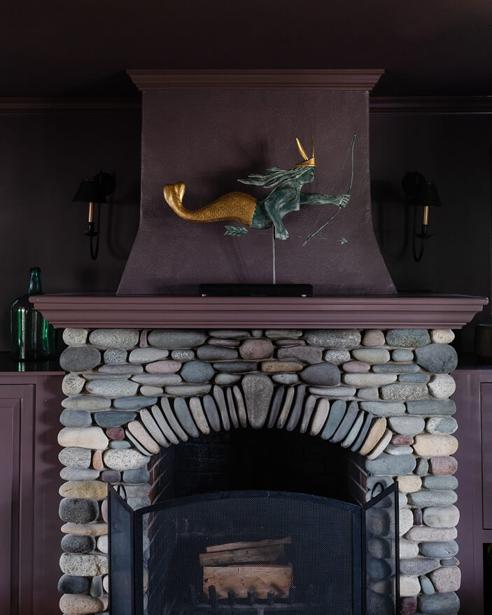 Moody family room with dark purple walls, natural cobblestone fireplace, and coastal design in a Martha’s Vineyard home.