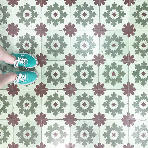Historic concrete tiles in light and dark green with burgundy accents in Havana, Cuba. Captured by Sarah Scales wearing green Vans.