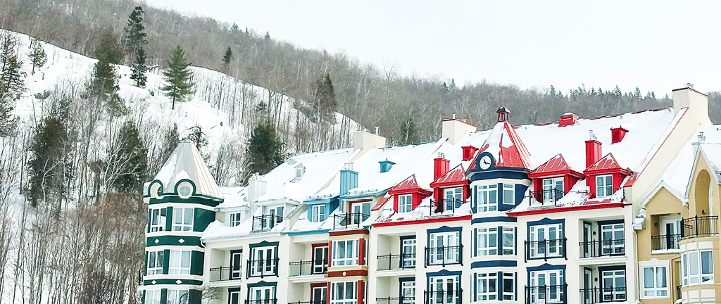 Mountain architecture with aqua and red rooftops, bold green, yellow, and red siding at the base of Mont Tremblant, Quebec.