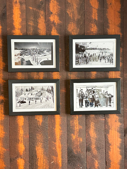 Restaurant interior with natural wood plank walls, vintage black and white ski photography, and rustic charm for design inspiration.