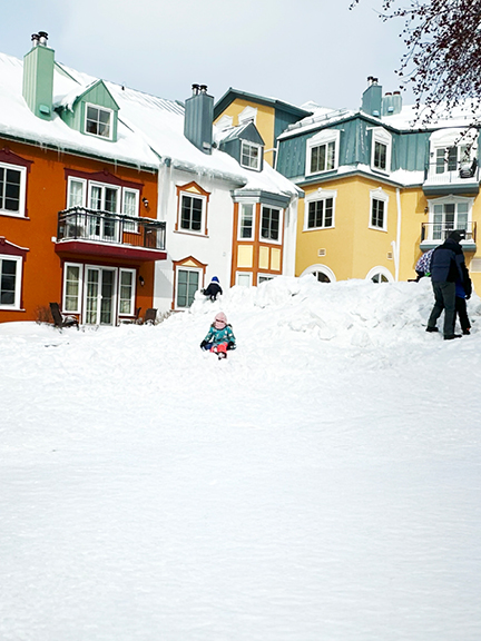 Travel to Mont Tremblant to see bold architecture with dark orange and light green roofs, yellow and blue facades, standing out against snowy peaks.