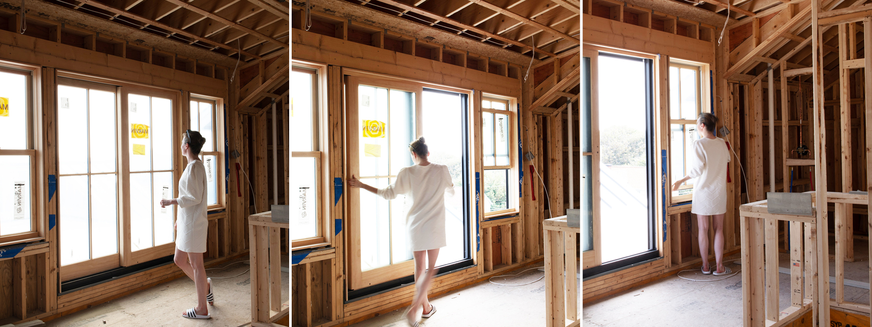 Sarah on-site at a new construction home on the South Shore, overseeing a full-service interior design project in Boston. She stands in a white dress near sliding doors and Marvin windows with rough framing visible.