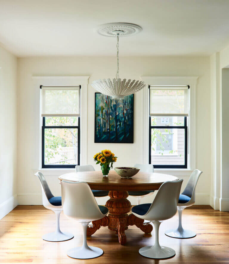 A historic Brookline home dining space with a vintage-inspired table, Saarinen tulip chairs, and artwork from the client’s collection.