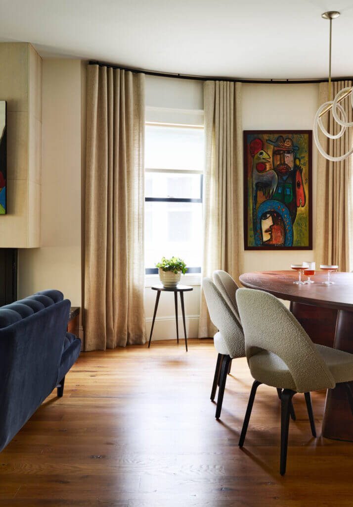 A historic Brookline home dining room design with a walnut table, boucle Knoll chairs, and neige drapery panels, blending classic and modern style.
