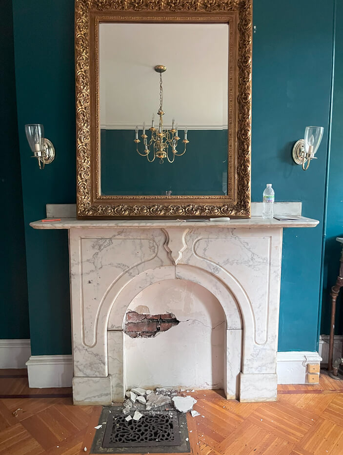 Original marble fireplace in a historic brownstone’s formal living room, to be salvaged and reused during the renovation process.