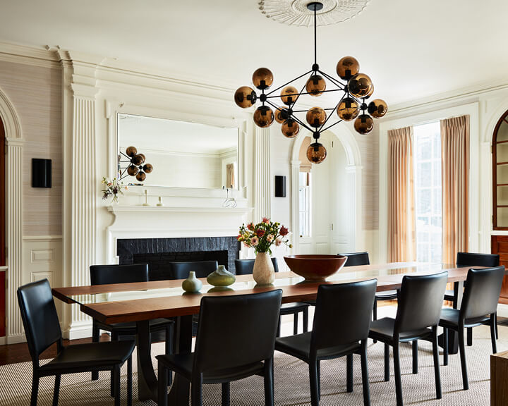 Formal dining room with custom table, modern lighting, and black leather chairs, illustrating designing for a historic home.