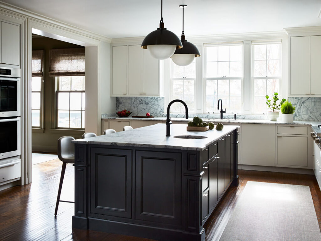 A modern kitchen in a historic Concord home with updated cabinet doors, a black-painted island, and new lighting for a fresh look.