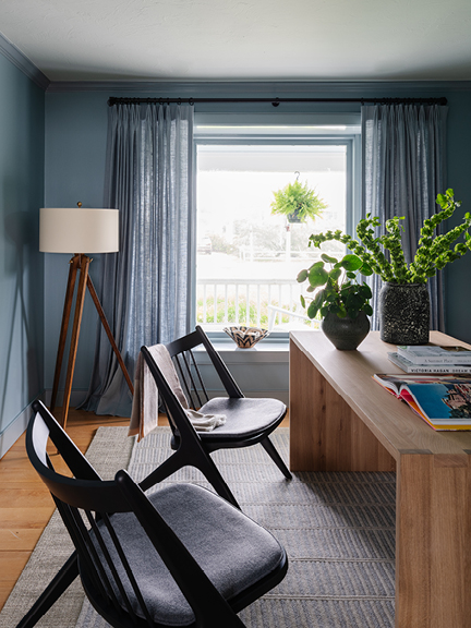 Home office with light blue walls, drapery panels, waterfall desk, and Danish-inspired black cherry lounge chairs from Room and Board.