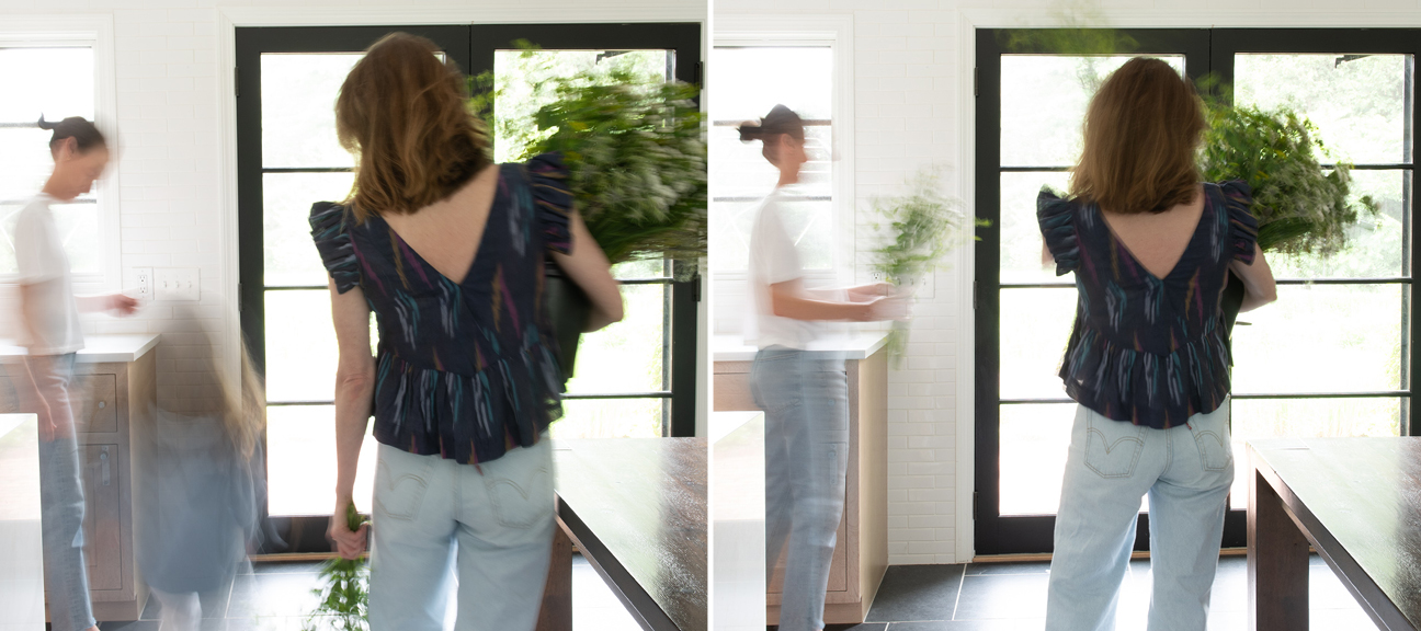 Designer onsite reviewing interior plans with client, wearing casual outfit and carrying fresh bouquet of flowers.