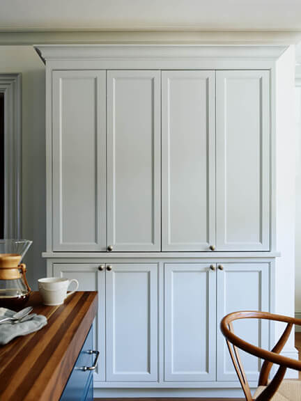 Light grey custom cabinets, inset with a beaded detail and classic cabinet doors, designed to look like a free-standing piece of furniture.
