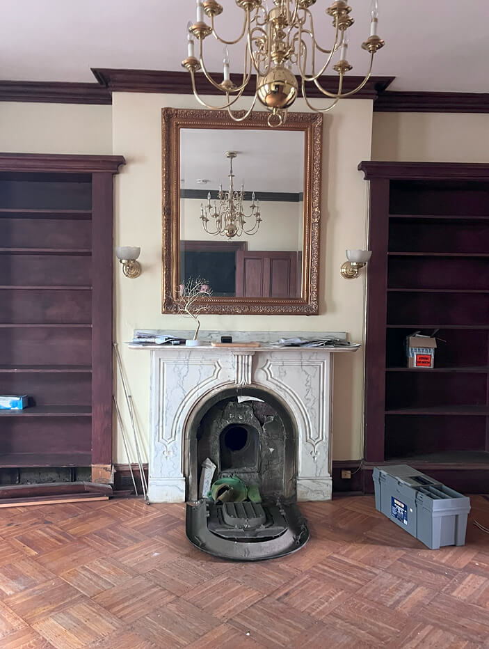 Boston brownstone renovation featuring the formal living room with original wood built-ins and parquet flooring, set to be removed and replaced with modern updates.