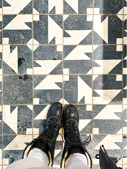 Black and white geometric floor tiles in Montreal, dusted with winter storm debris, paired with white pants and black leather L.L. Bean boots.