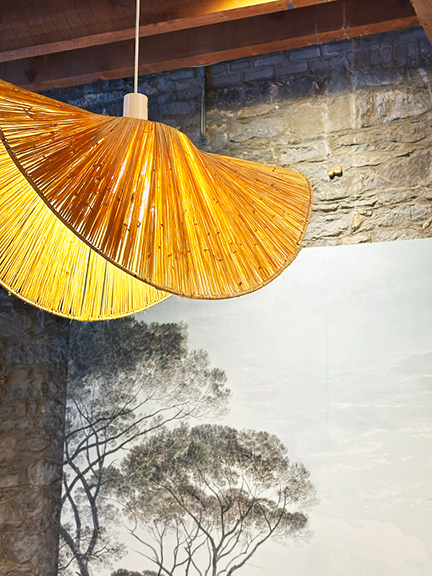Visit Montreal in the Winter to see a uniquely shaped woven pendant light with landscape art, set against historic stone walls at Maison Pepin.