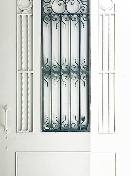 Visit Montreal in the Winter, showcasing a historic white-painted door with classic hardware, contrasted with wrought iron details on the building.