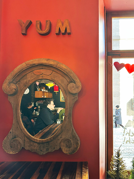 Visit Montreal in the Winter, showcasing the interior design at Olive et Gourmando with red walls, vintage mirror, and wooden letters spelling "YUM."