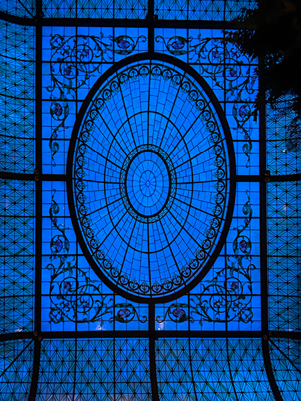 Nighttime view of the Palm Court glass ceiling at the Park Plaza Hotel in New York City, with dramatic lighting and architectural detail.