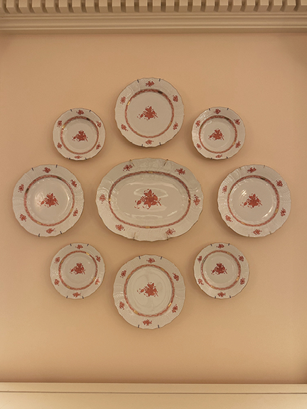 Vintage plates on an off-white wall with dentil molding, a traditional detail offering NYC interior design inspiration at Hearst Tower.