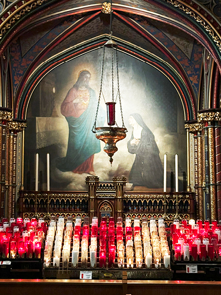 A collection of red and white prayer candles at Notre-Dame Basilica’s altar, framed by old-master artwork, arches, and intricate details.