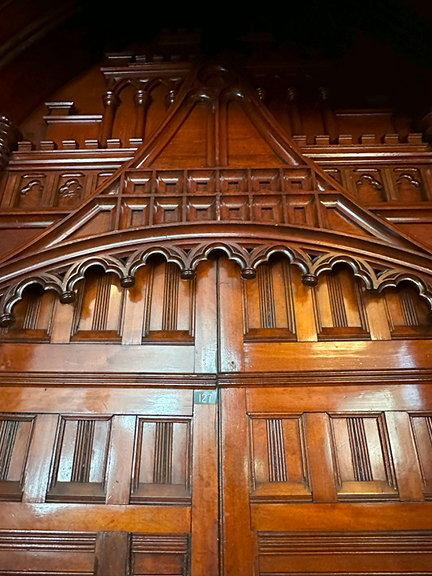 The aged wooden doors of Notre-Dame Basilica in Montreal feature natural tones, fluted details, and grand carved nubs, rich with history.