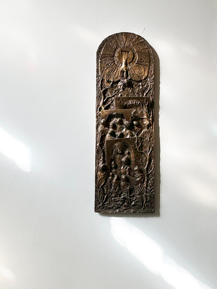 Visit Montreal in the Winter to see a detailed bronze relief at Notre-Dame Basilica, set against white gallery-like walls in a sunlit corridor.