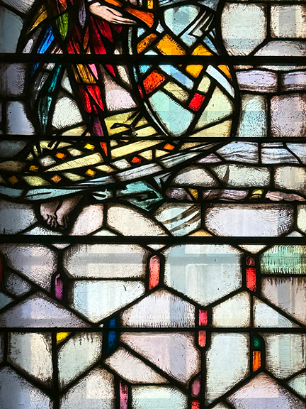 A stunning stained glass window at Notre-Dame Basilica in Montreal featuring soft pastels, vibrant reds, and deep tones in a historic design.