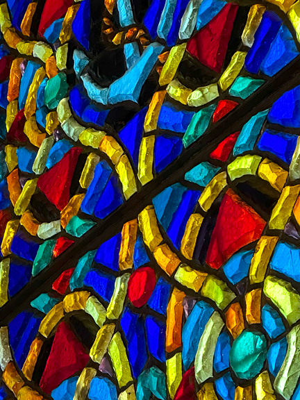 A three-dimensional stained glass panel at Notre-Dame Basilica in Montreal, featuring lapis blue, crimson red, lime green, and golden orange.