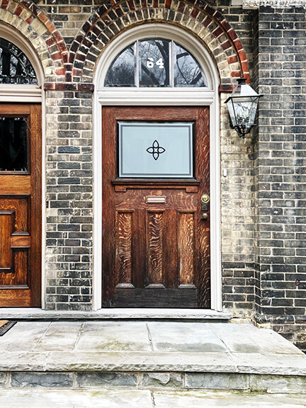 Close-up of an ornate door in historic Toronto, showing wood carving, ironwork, and traditional proportions.