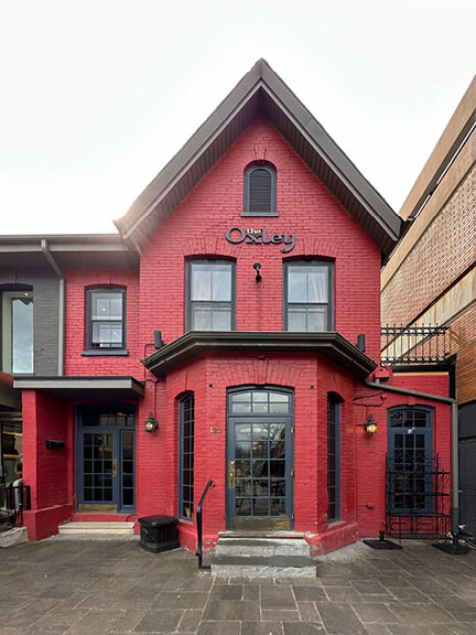 Painted red historic building in Yorkville, Toronto, with black-framed windows and doors, offering a modern update to a classic shopping district structure
