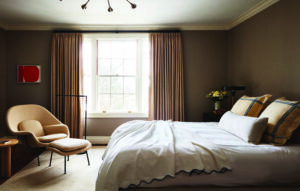 Open floor plan problems solved with scaled furniture, drapery, and rugs in a taupe bedroom within a historic home.