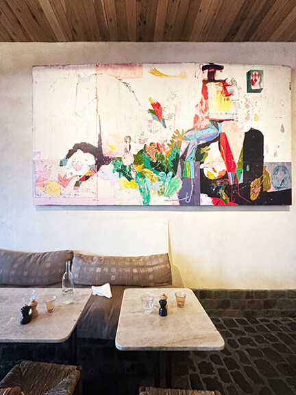 Abstract art, plaster walls, wood ceiling, and tumbled stone flooring in a West Hollywood restaurant. Shop and Dine LA.