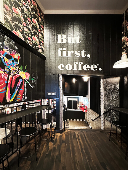 Bold graffiti art and black walls inside Alfred’s Coffee in West Hollywood, with eclectic artwork and moody interior lighting.