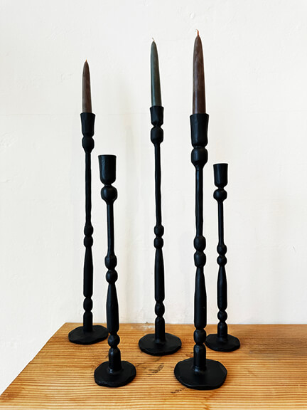 Black candlesticks on wood shelf against white stucco wall at Jenna Cooper, part of LA interior design showrooms