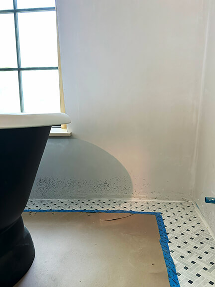 Black bathtub and basketweave tile floor in a classic bathroom with vintage-inspired interior design