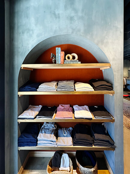 Retail interior design in Los Angeles with blue plaster walls, arched architectural details, and natural wood shelving.