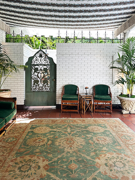 Entryway at Chateau Marmont featuring vintage furniture, painted brick walls, and a striped awning, capturing classic Hollywood style.