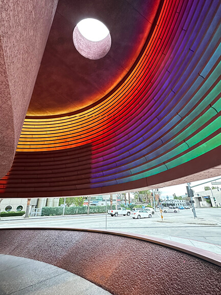 Retail architecture at The Webster West Hollywood with pastel pink walls and glowing rainbow lights highlighting the entry and facade.