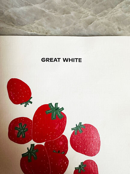Strawberry-themed menu design at Great White in West Hollywood, blending playful graphics with a relaxed café setting.
