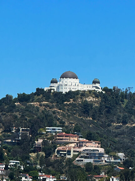 Griffith Observatory in Los Angeles sits atop the hills, with white walls and a stately dome overlooking the city’s sprawling landscape.