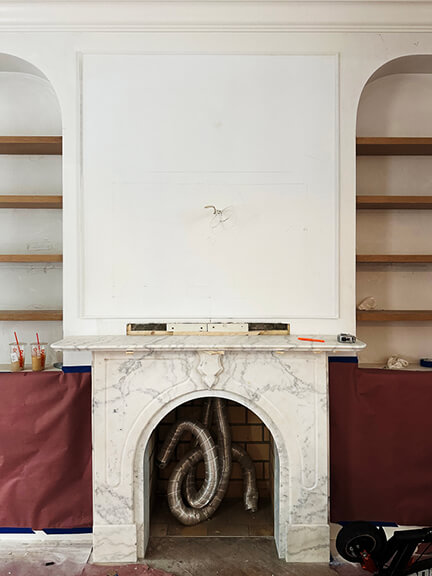 Original marble fireplace and custom shelving in a Boston brownstone renovation living room with historic details
