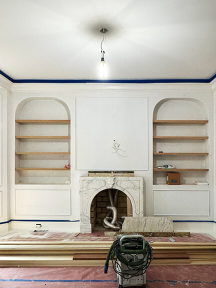 Custom millwork and shelving frame the fireplace in this historic Boston brownstone living room with traditional details
