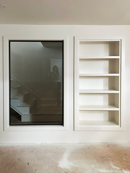 Custom home gym with internal window and shelving in a Boston brownstone renovation by New England interior designer