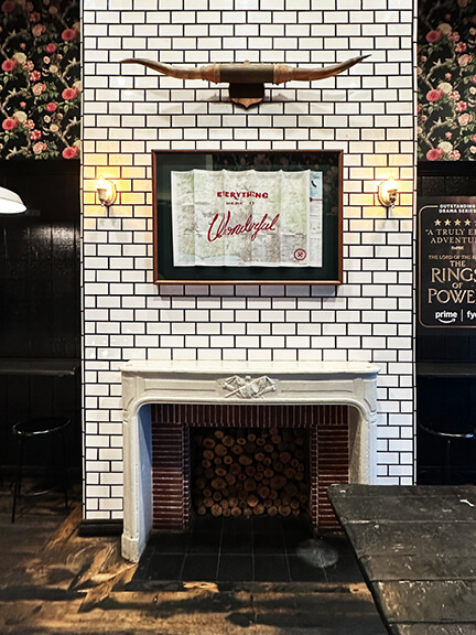 Fireplace mantel detail in a Los Angeles coffee shop with white subway tile and black grout, blending vintage charm with modern finishes.