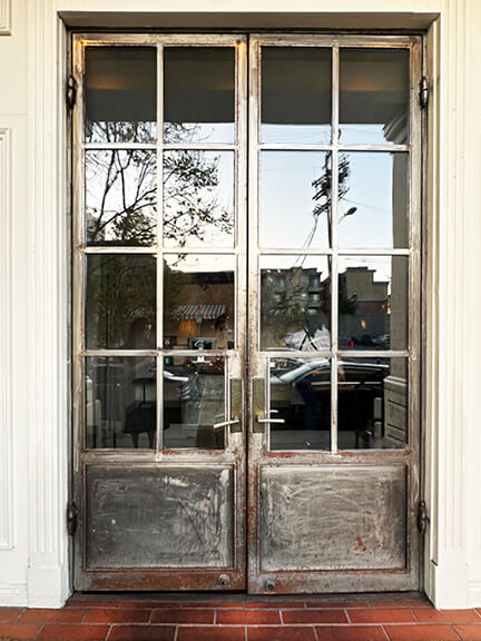 Vintage metal doors at A.O.C. restaurant in Los Angeles, designed by Nickey Kehoe to add a historic, architectural touch to the entry.