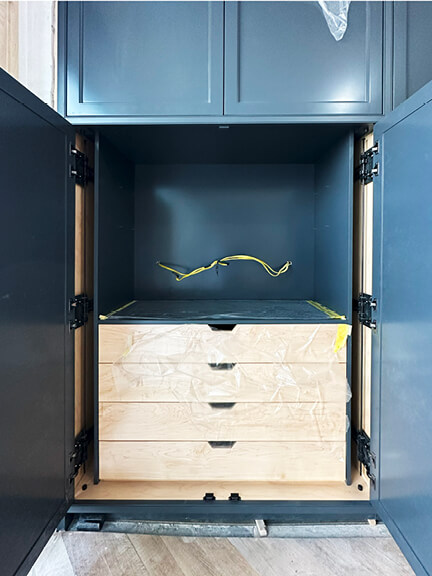 Navy blue pantry with pocket doors hides appliances in a breakfast station designed for a historic Boston brownstone