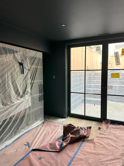 Navy blue media room with custom shelving and double doors leading to an exterior patio in a Boston brownstone