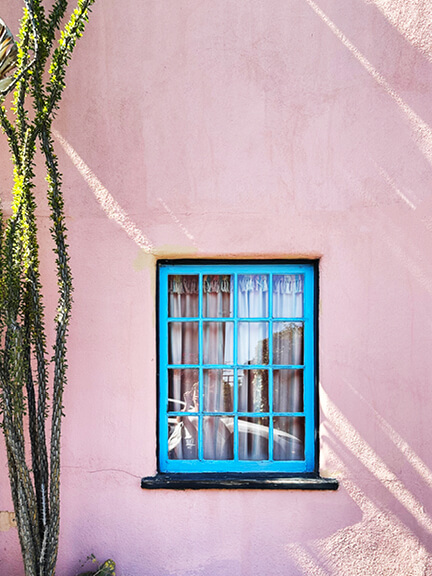 Pink stucco home with bright blue window trim, an example of playful LA architecture in the Los Feliz hills.