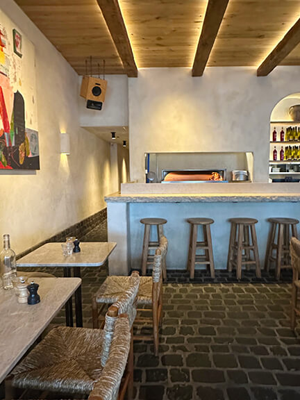 Plaster walls, a natural wood ceiling, and tumbled stone flooring at Great White create a calm, coastal-inspired restaurant interior.