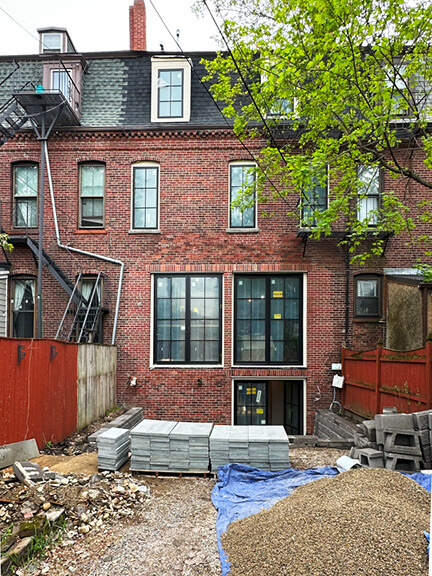 Rear elevation of a Boston brownstone renovation with new doors and windows blending modern updates with historic detailing