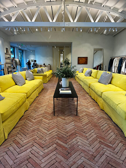 Jacquemus retail interior in LA with terracotta herringbone tiles and yellow sofas. A standout in Los Angeles Shopping and Dining.