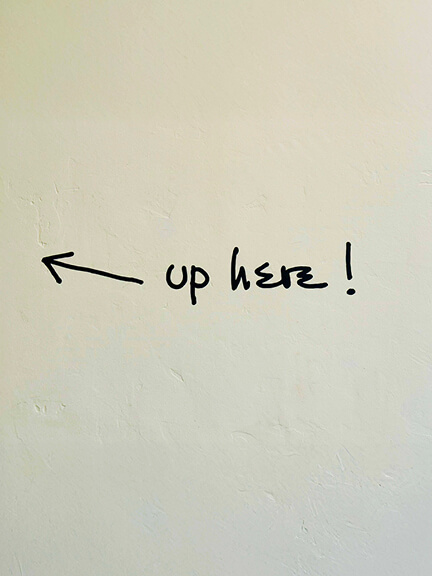 Stair signage reading “Up Here” leads to the second level of a Los Angeles showroom, combining retail design with playful, modern interior details